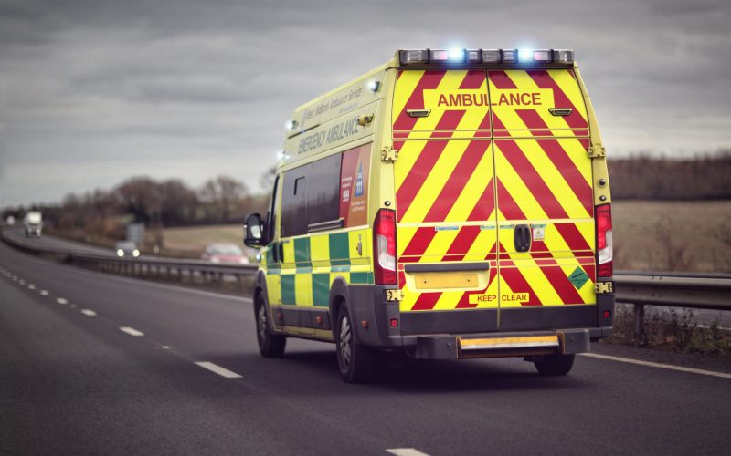 British ambulance responding to an emergency in hazardous bad weather driving conditions on a UK motorway